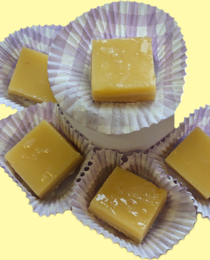 Eleven lemon squares next to a knife.